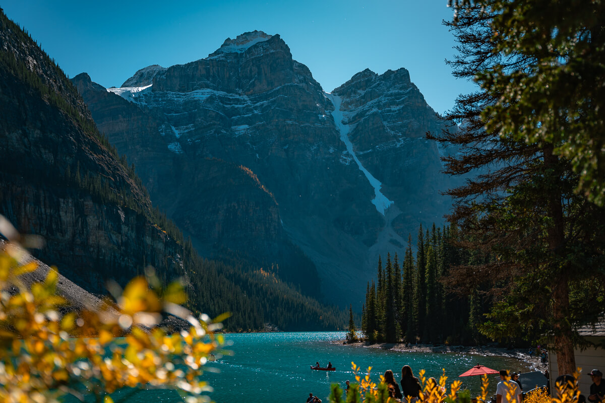 Moraine Lake peaks dusted in snow with yellow shrubs framing the photo
