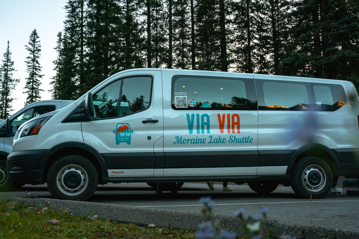 Via Via Moraine Lake shuttle with purple flowers in the foreground